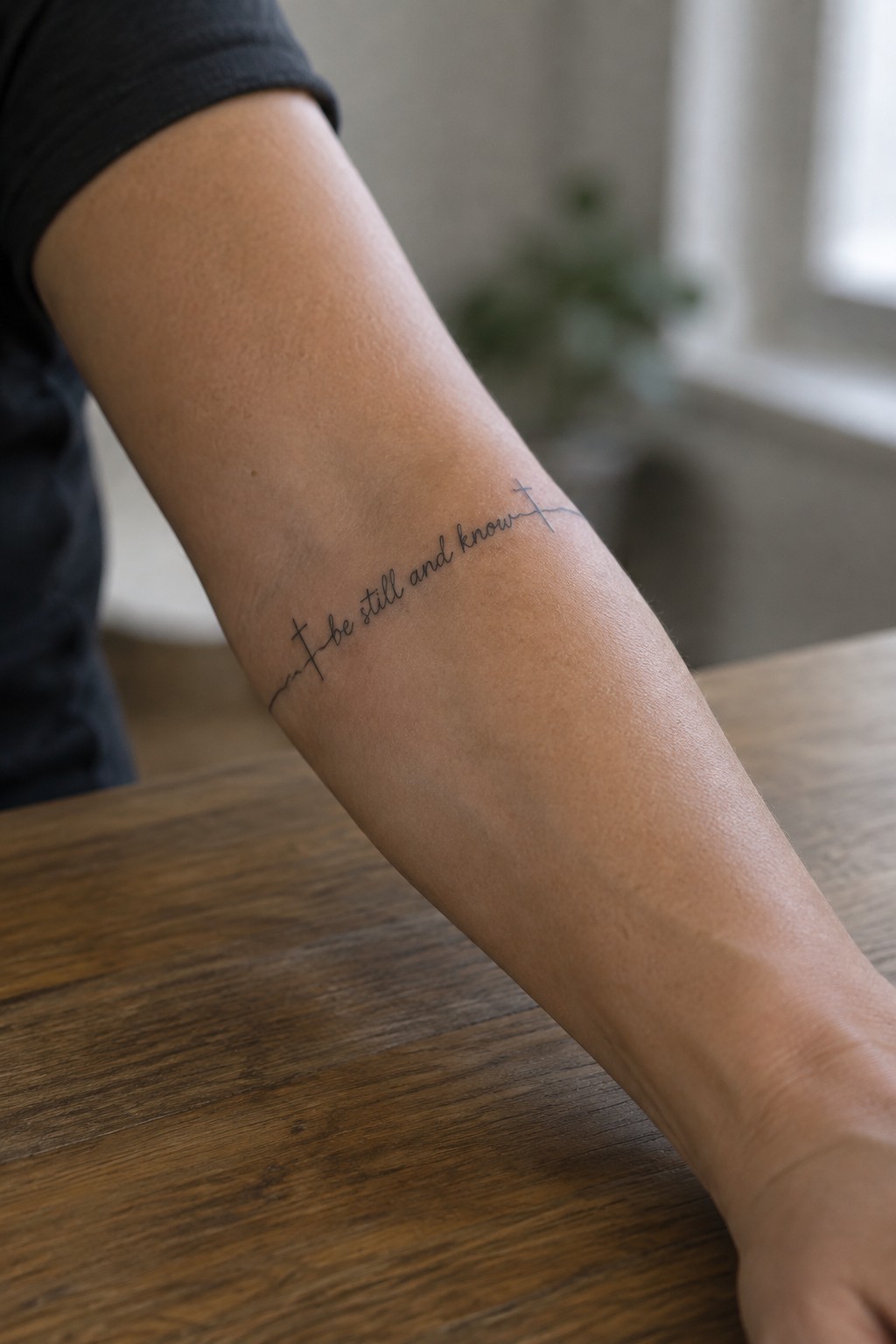 Forearm in black shirt with cursive 