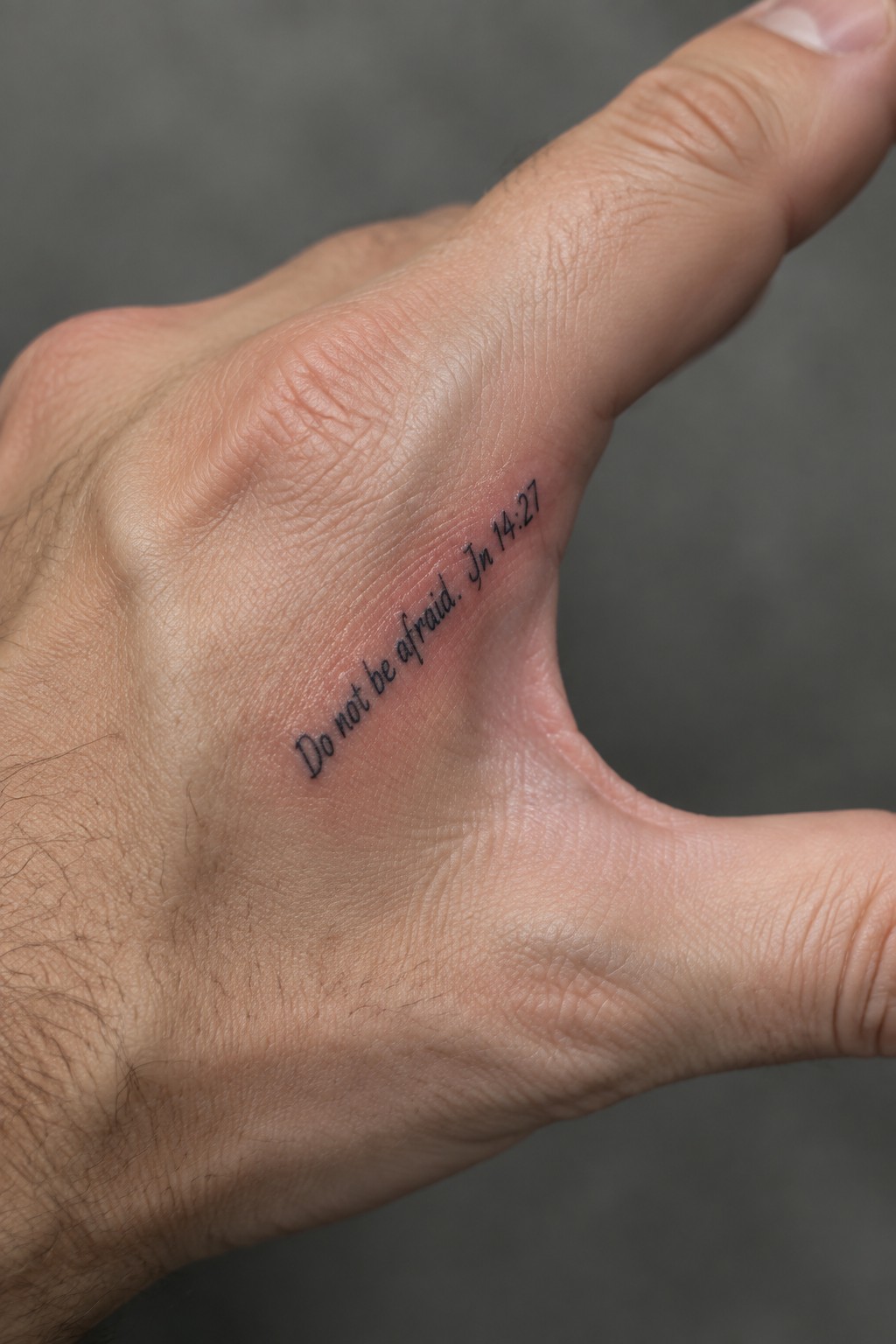 Close-up of hand with black tattoo reading 