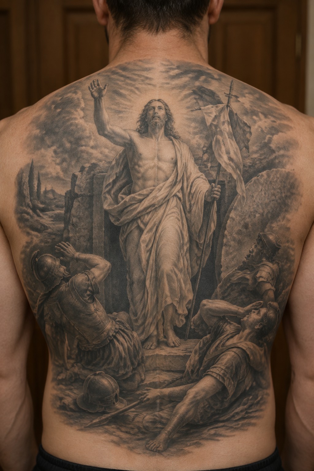Realistic black-and-gray tattoo of Jesus with flag among fallen Roman soldiers on back