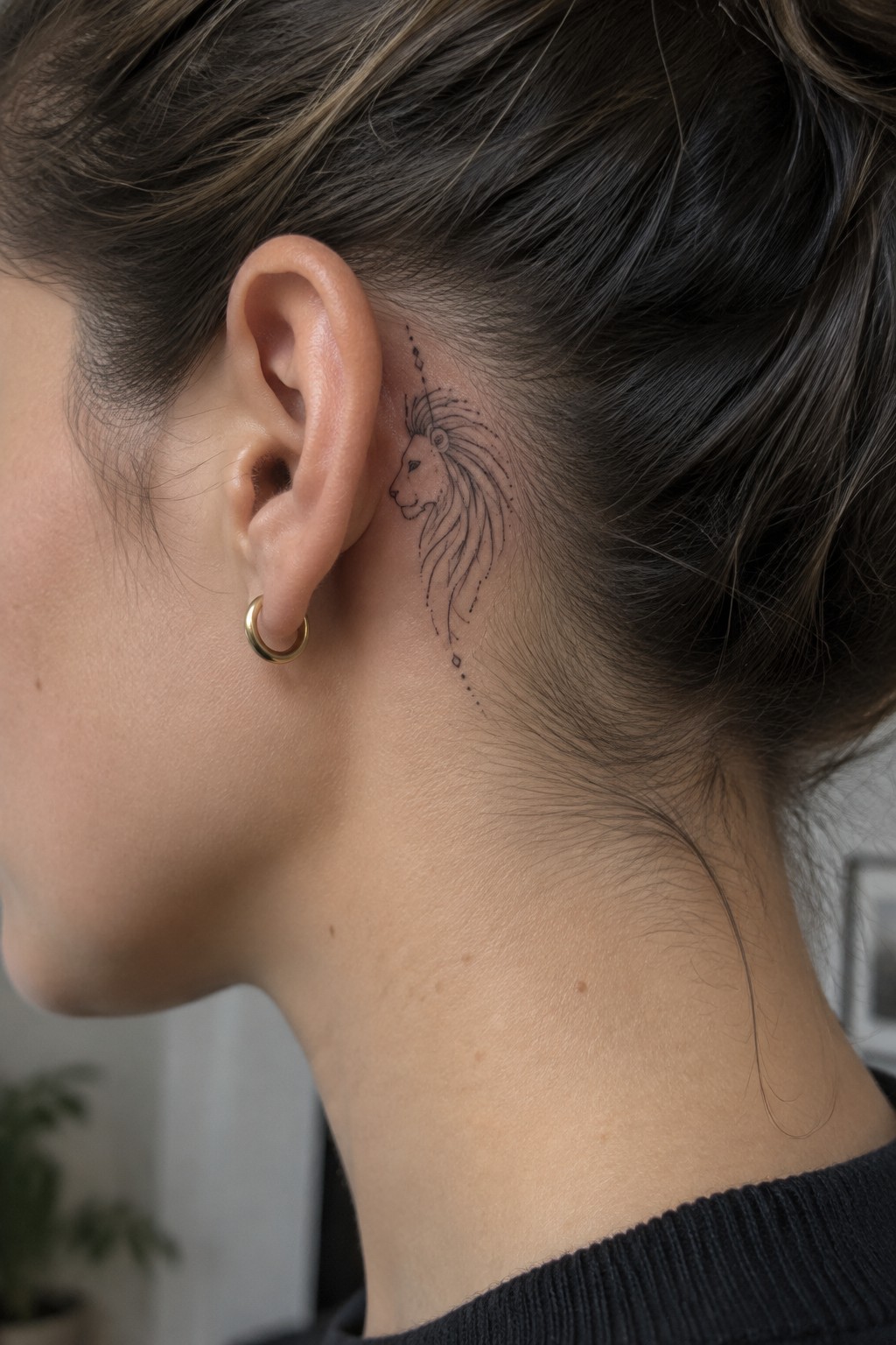 Woman's neck with minimalist lion tattoo behind ear and gold hoop earring