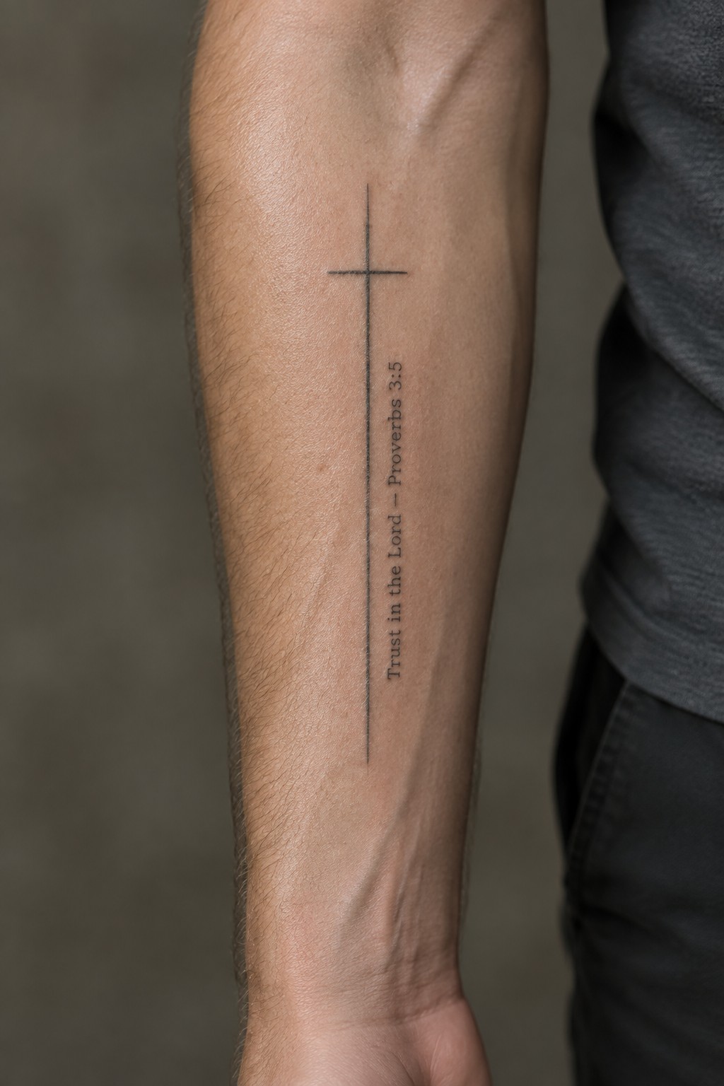 Forearm with thin black cross tattoo and vertical 