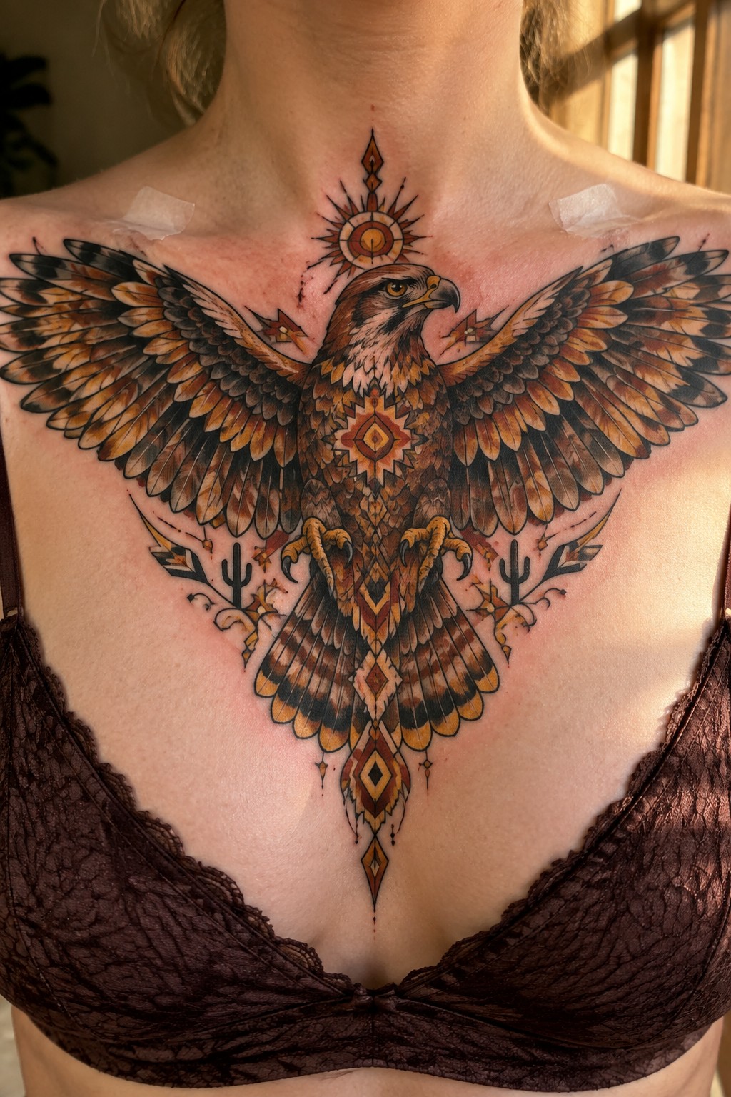 Fresh colorful eagle tattoo with geometric patterns above brown lace bra.