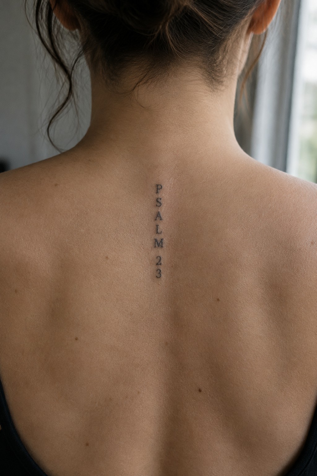 Vertical PSALM 23 tattoo in black ink on bare upper back