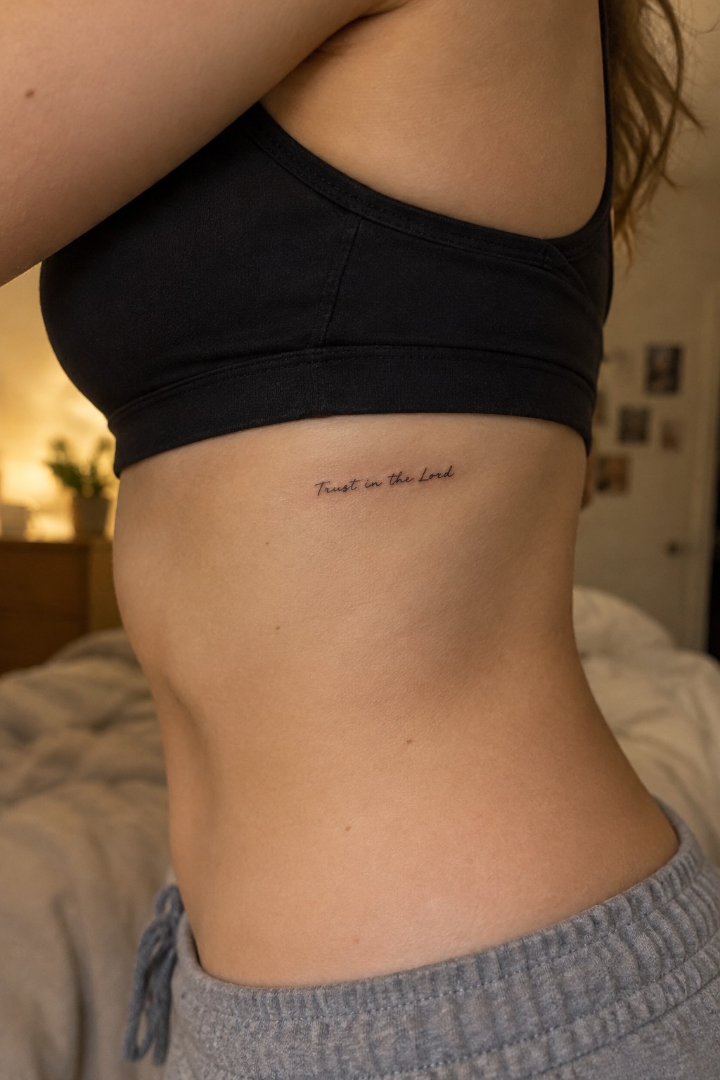 Torso in black crop top and gray sweatpants with cursive