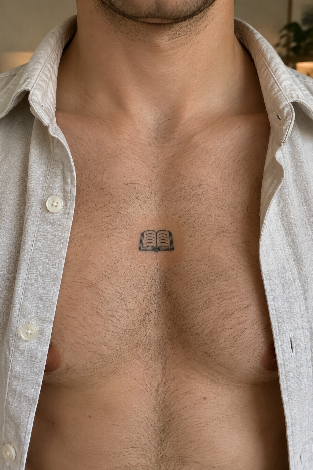 Open white shirt on hairy chest with small open book tattoo