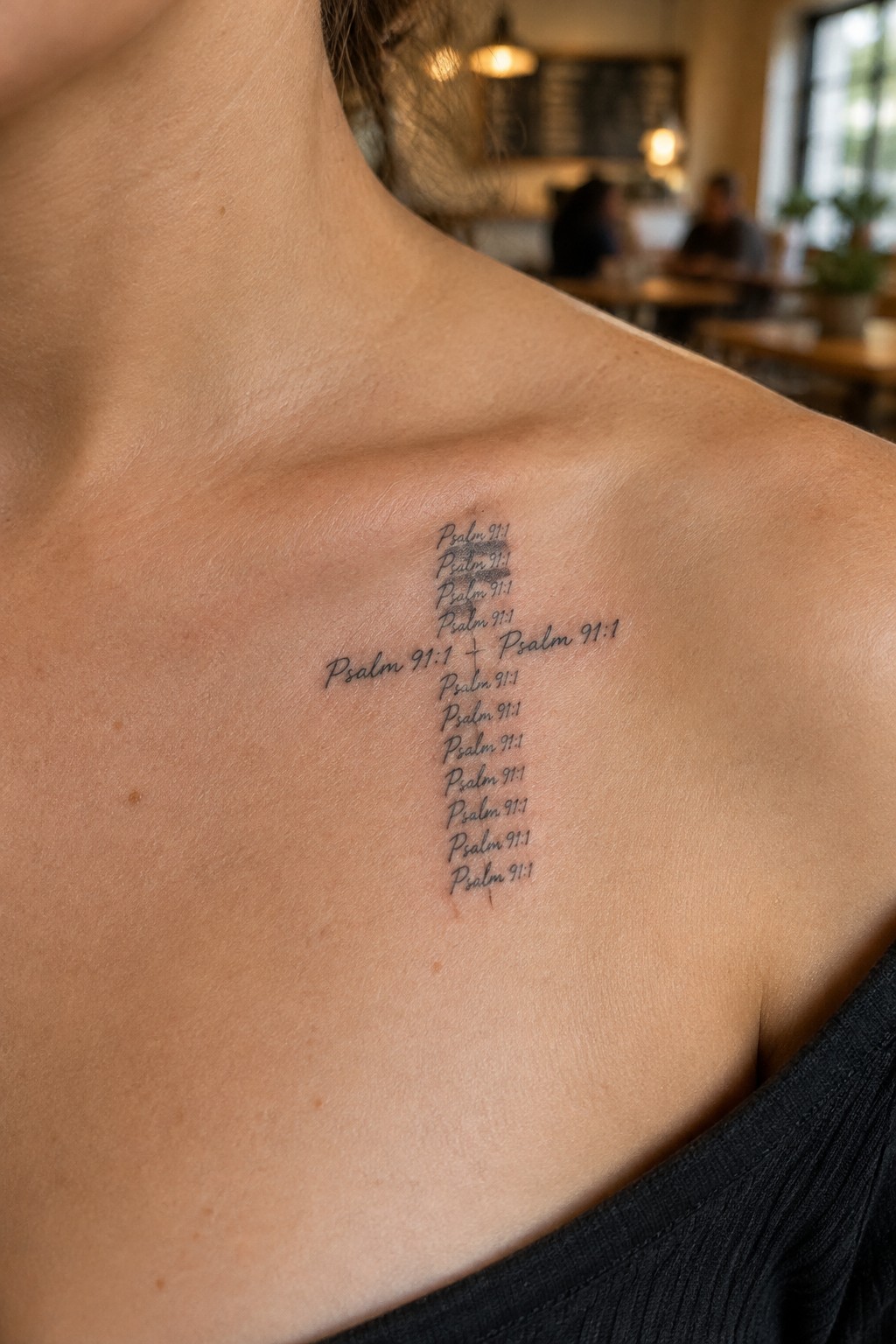 Small cross tattoo on upper chest formed by repeated lines of Psalm 91:1 text