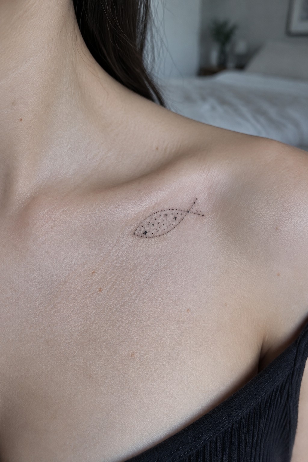 Small dotted fish tattoo with stars inside placed on the shoulder near the collarbone