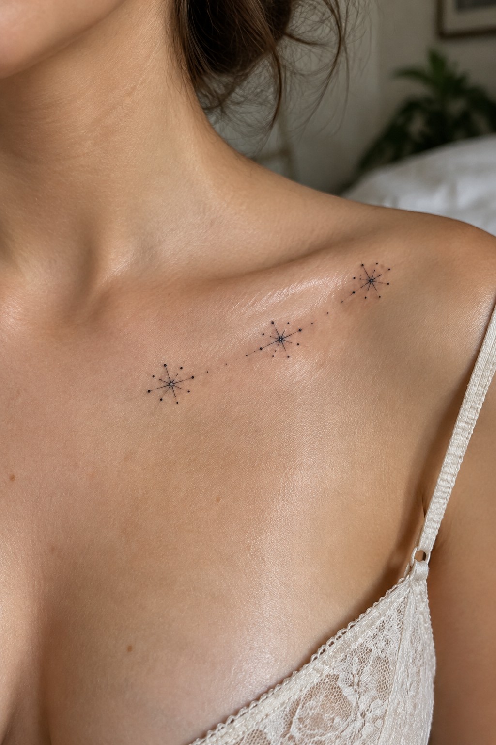 Fine-line black tattoo of three small starbursts connected by dots along a woman’s collarbone.
