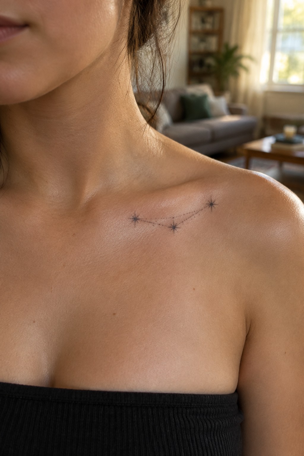 Woman's collarbone with constellation tattoo above black strapless top