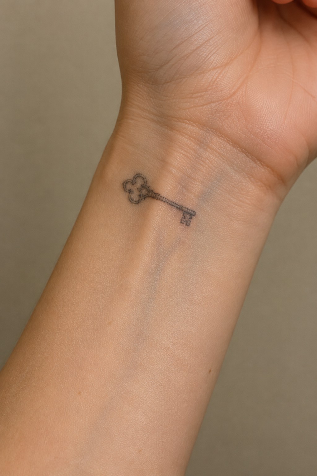 Small fine line skeleton key tattoo on the inner wrist