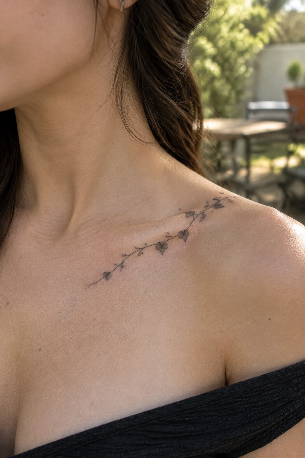 Woman in black off-shoulder top with delicate vine tattoo on shoulder