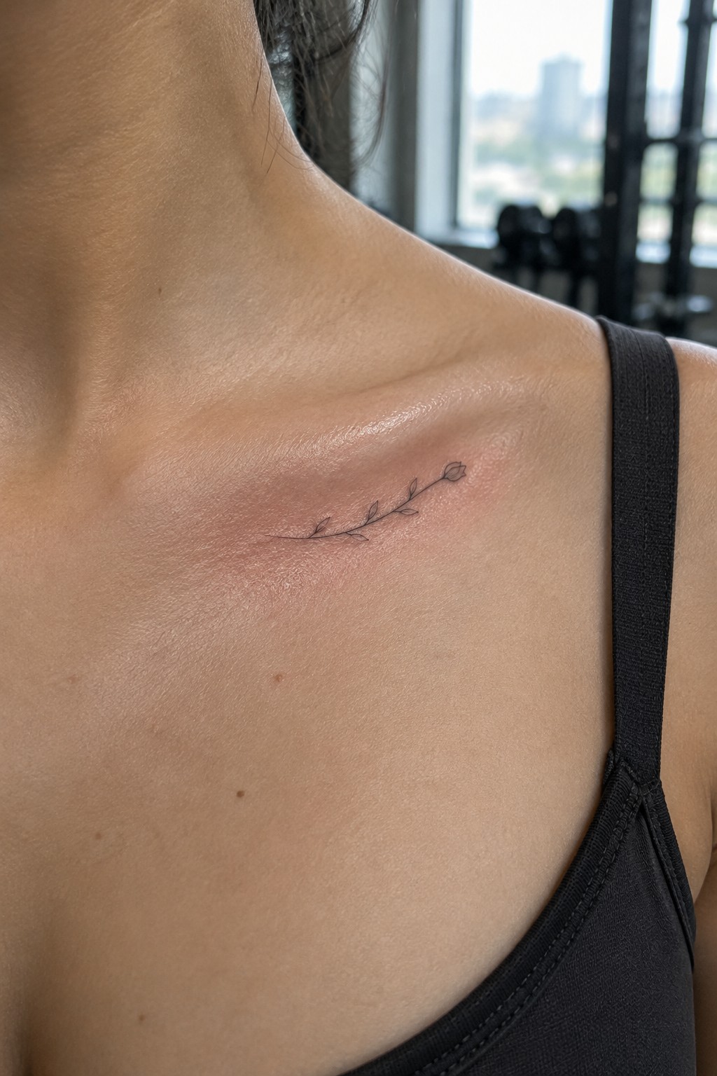Line art floral tattoo on reddened shoulder beside black tank top strap