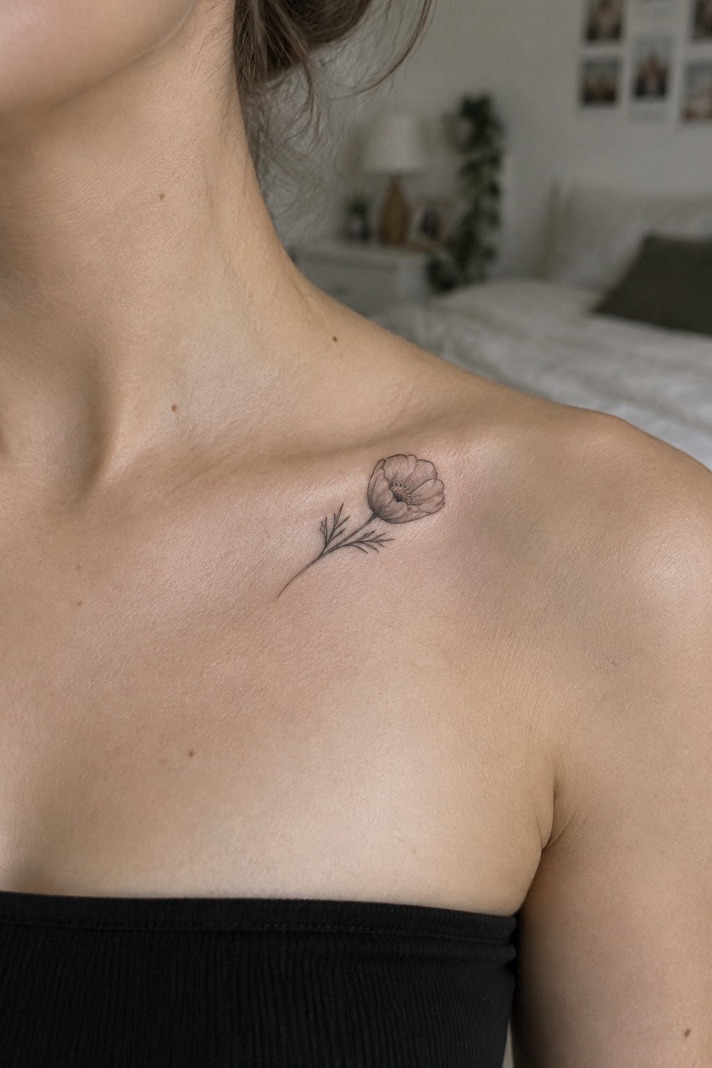Minimalist fine line poppy tattoo with stem on a woman's collarbone