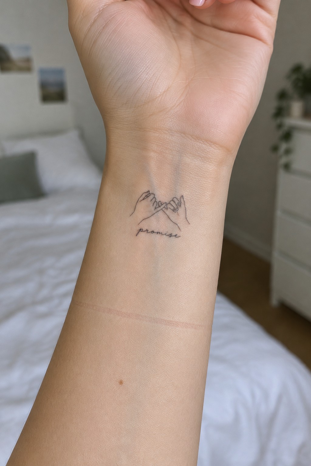 Wrist with minimalist line tattoo of two interlocked hands and 