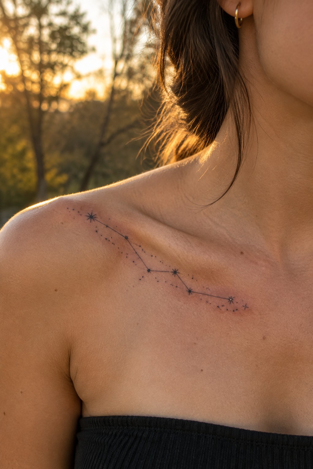 Fine-line constellation tattoo with connected stars and small dots stretching across a woman’s collarbone.