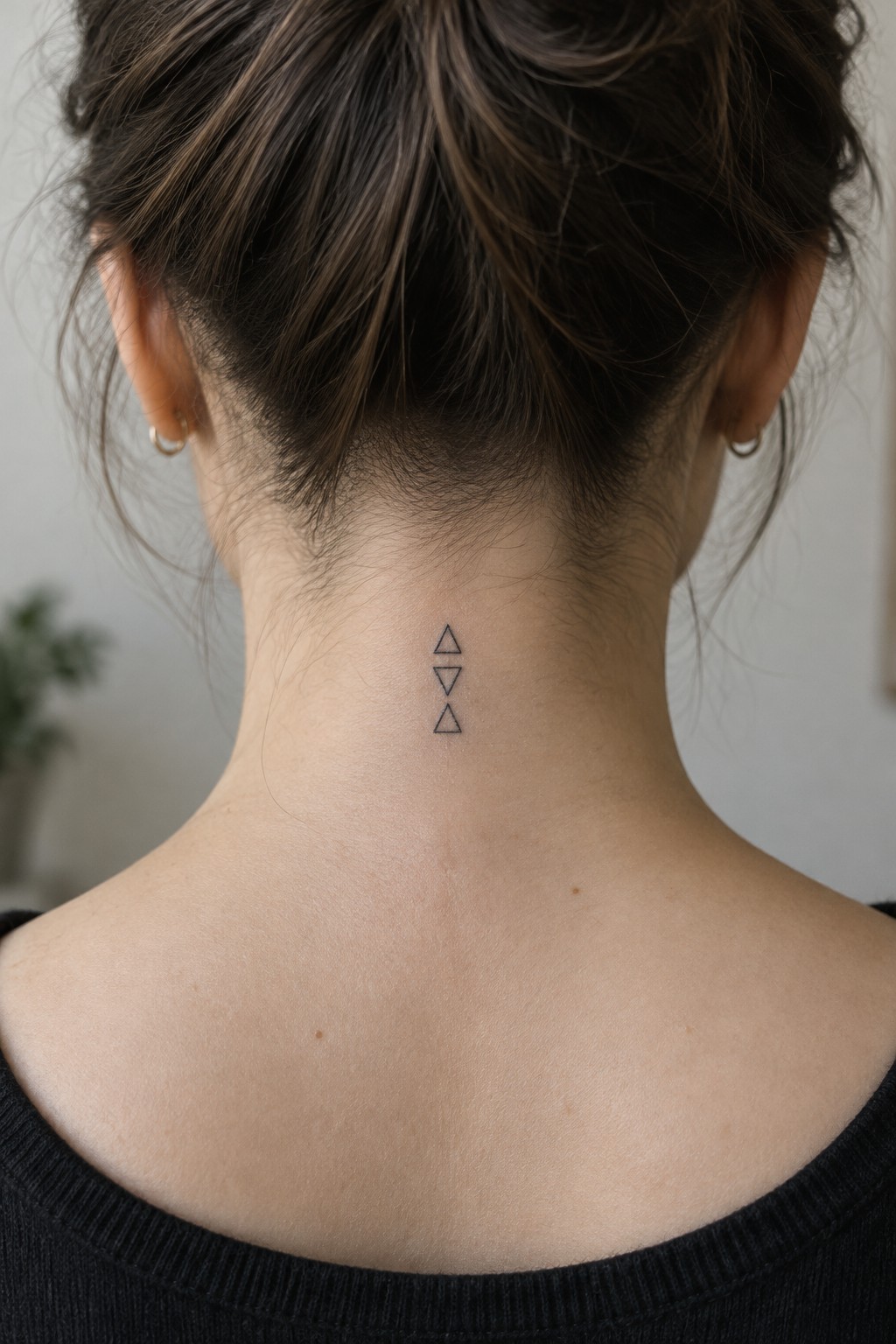 Three small outlined triangles arranged vertically in alternating directions at the nape of a woman’s neck.