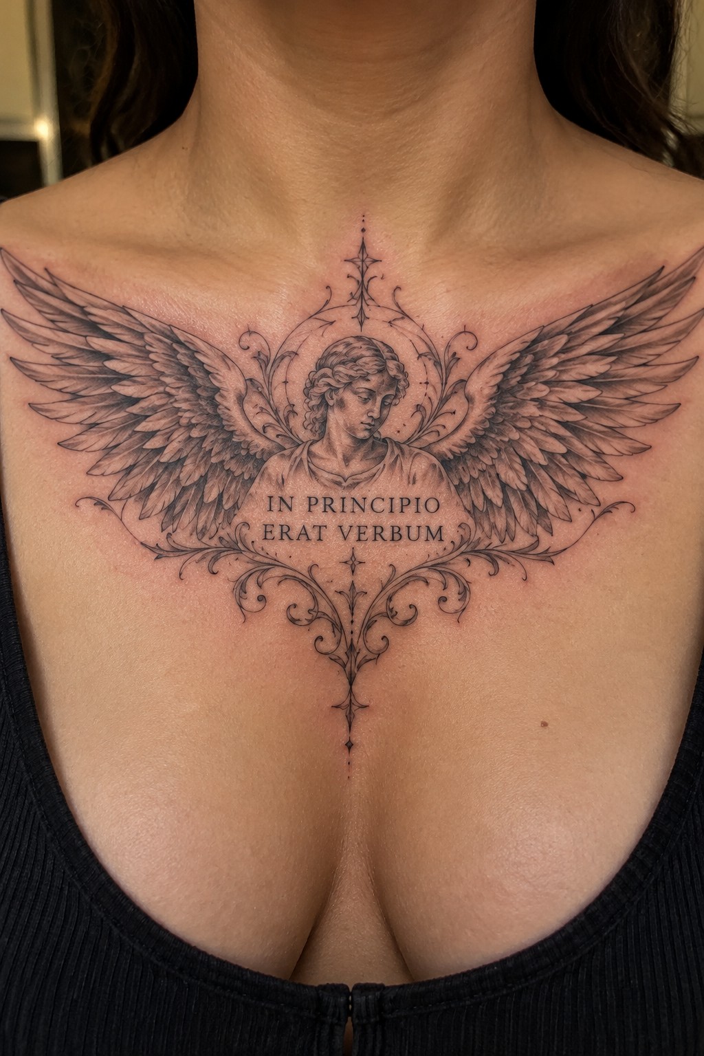 Intricate black and gray chest tattoo of winged angel with Latin text and ornate flourishes