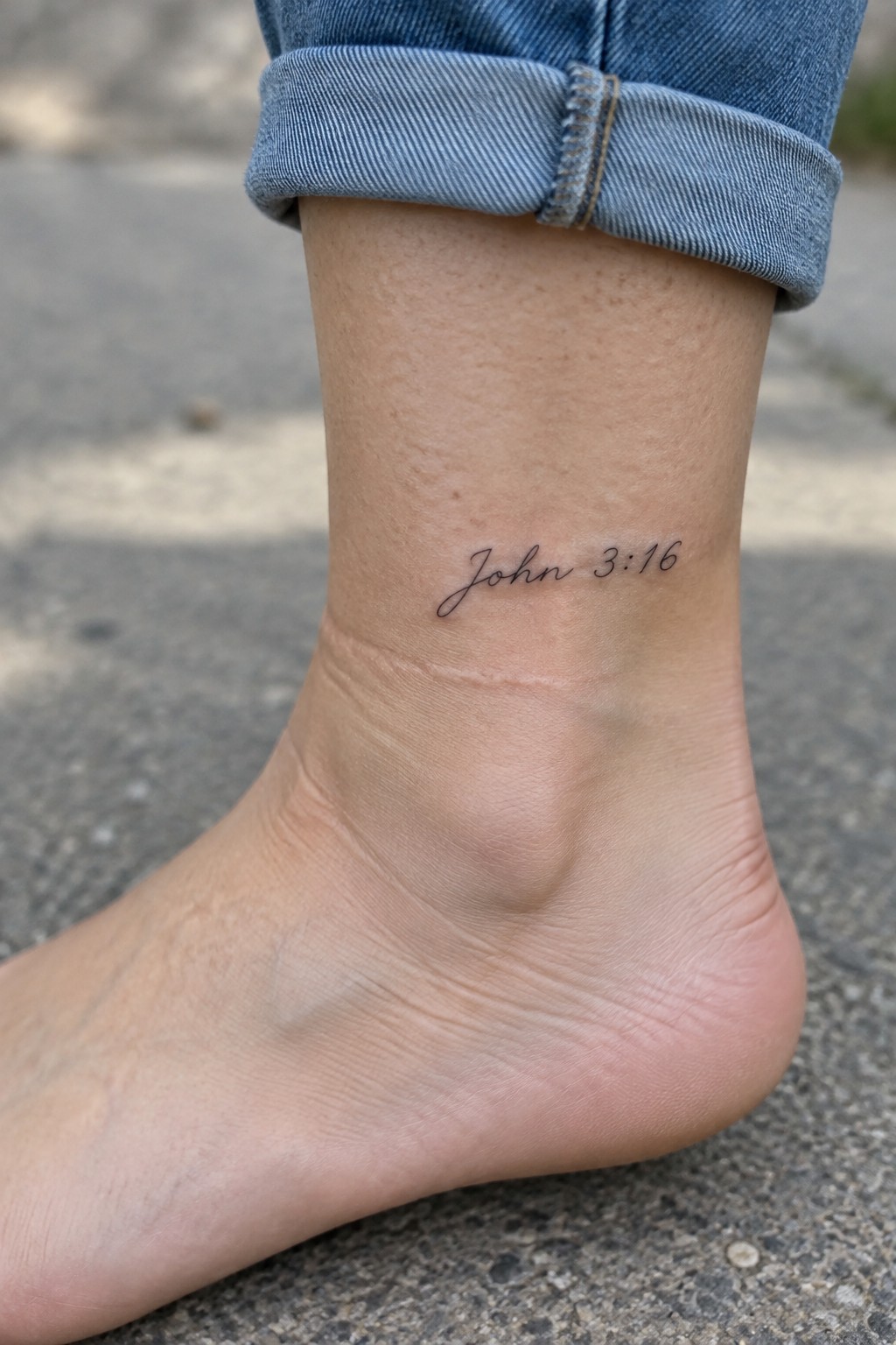 Cuffed blue jeans above bare ankle with cursive