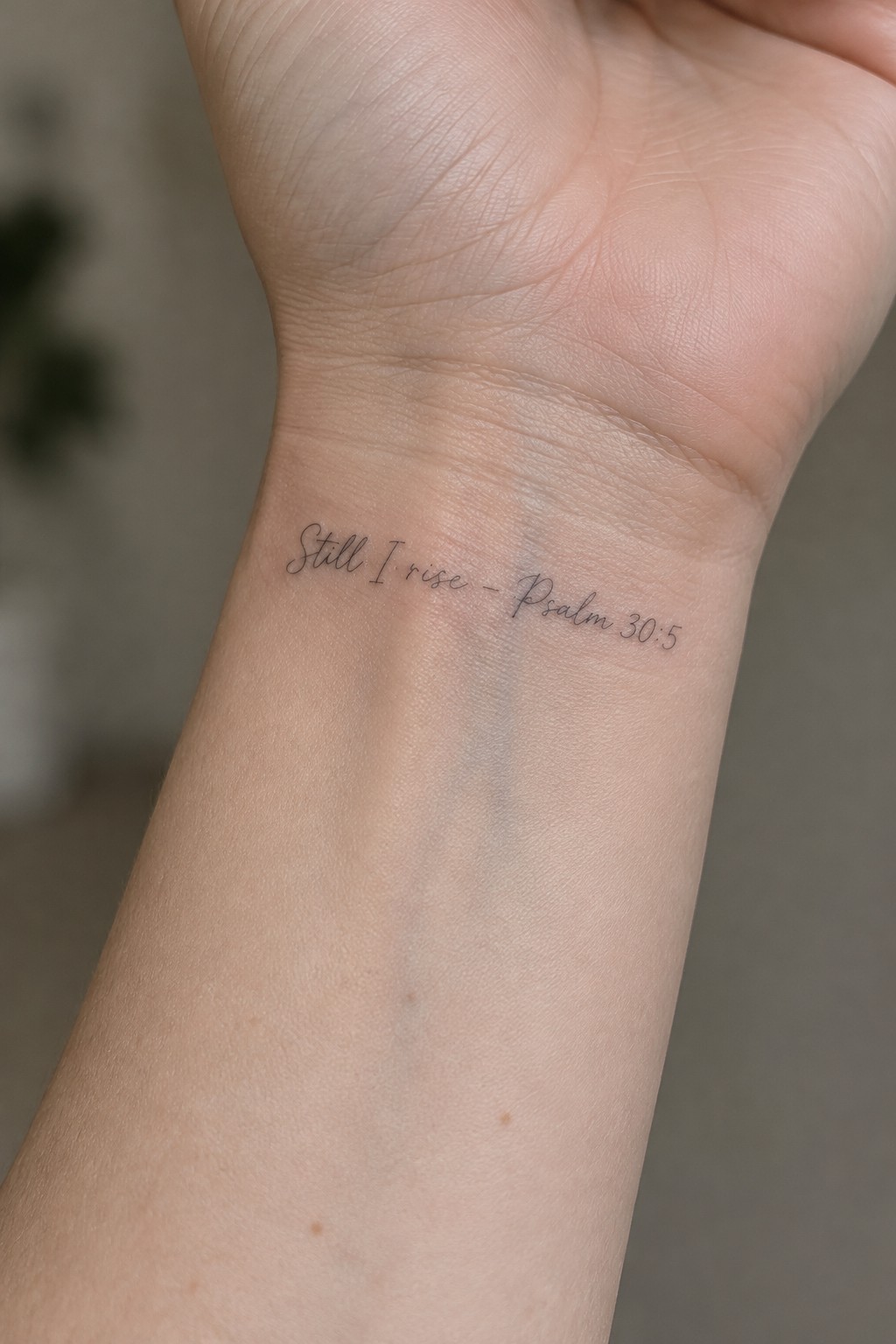 Wrist with cursive black tattoo reading