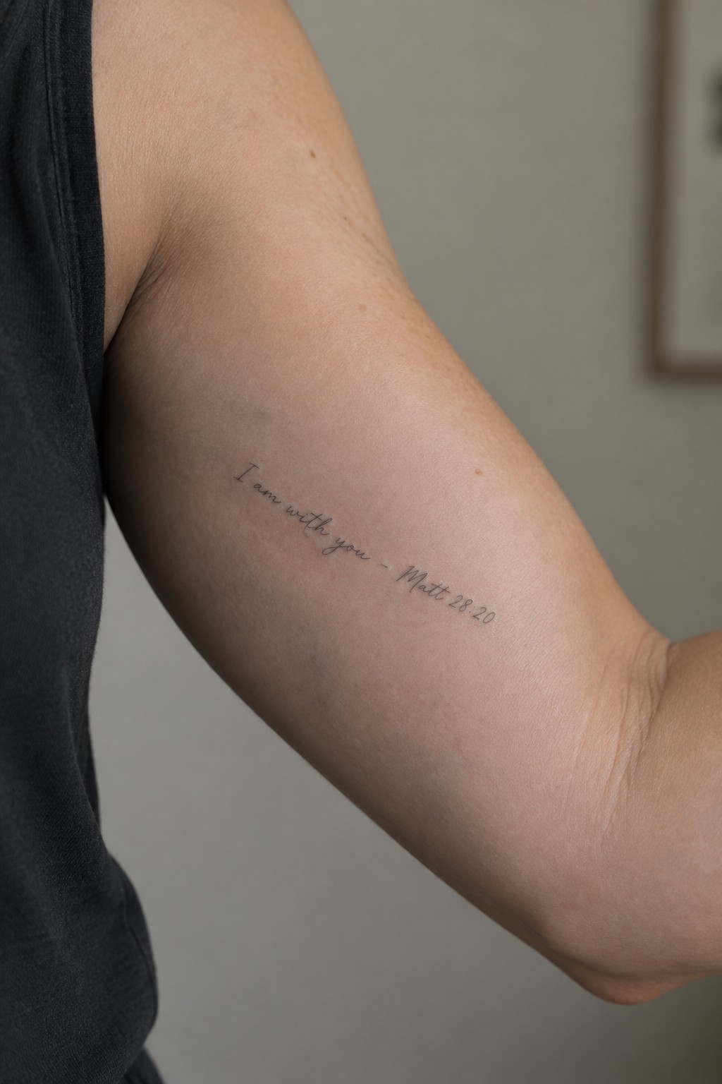 Fine line cursive tattoo on the inner upper arm that reads