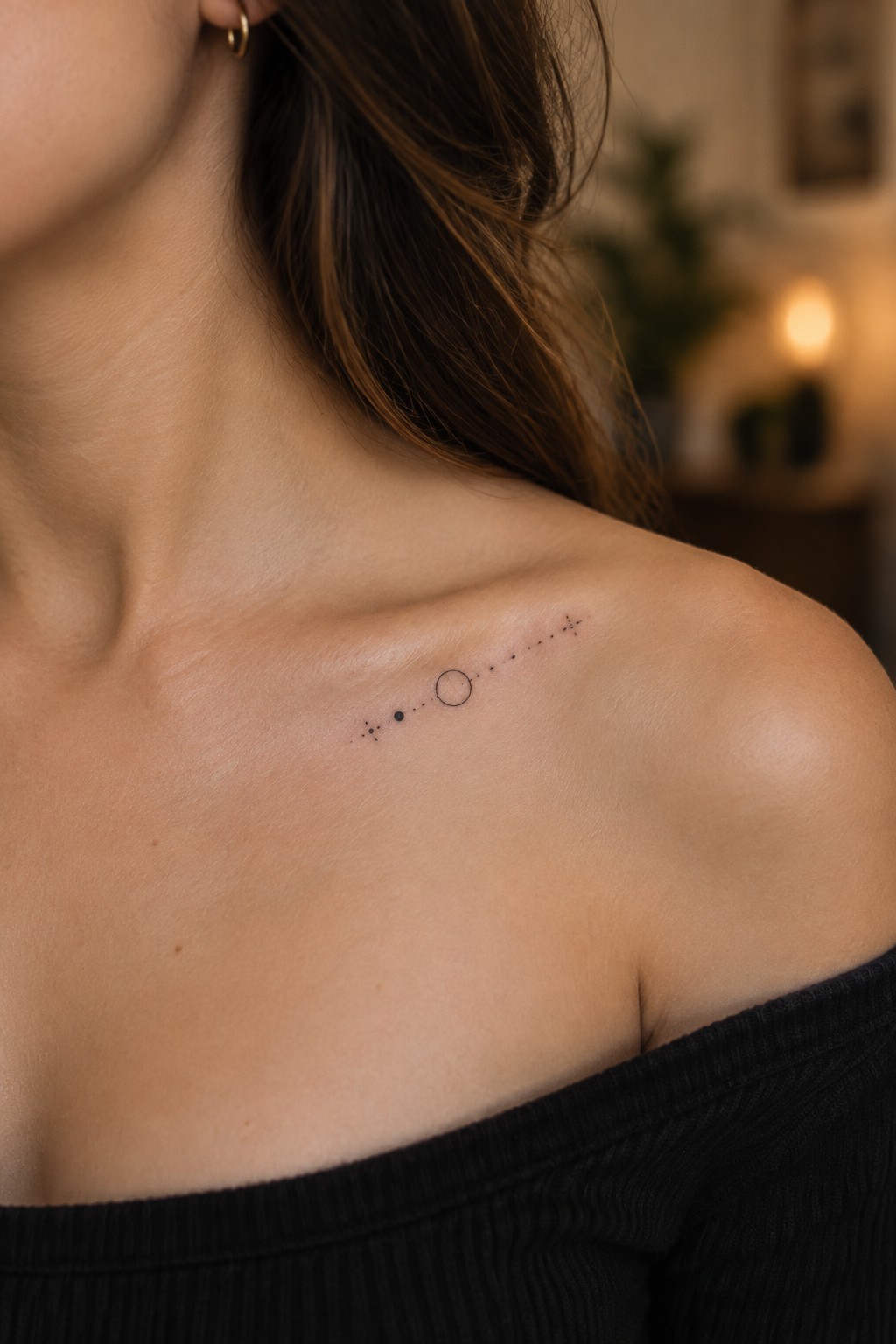 Woman's shoulder with celestial dot tattoo in black off-shoulder top