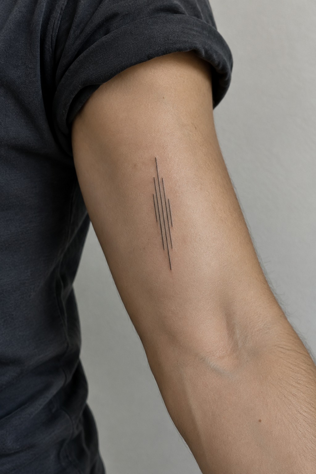 Upper arm in dark t-shirt with slanted black line tattoo on skin