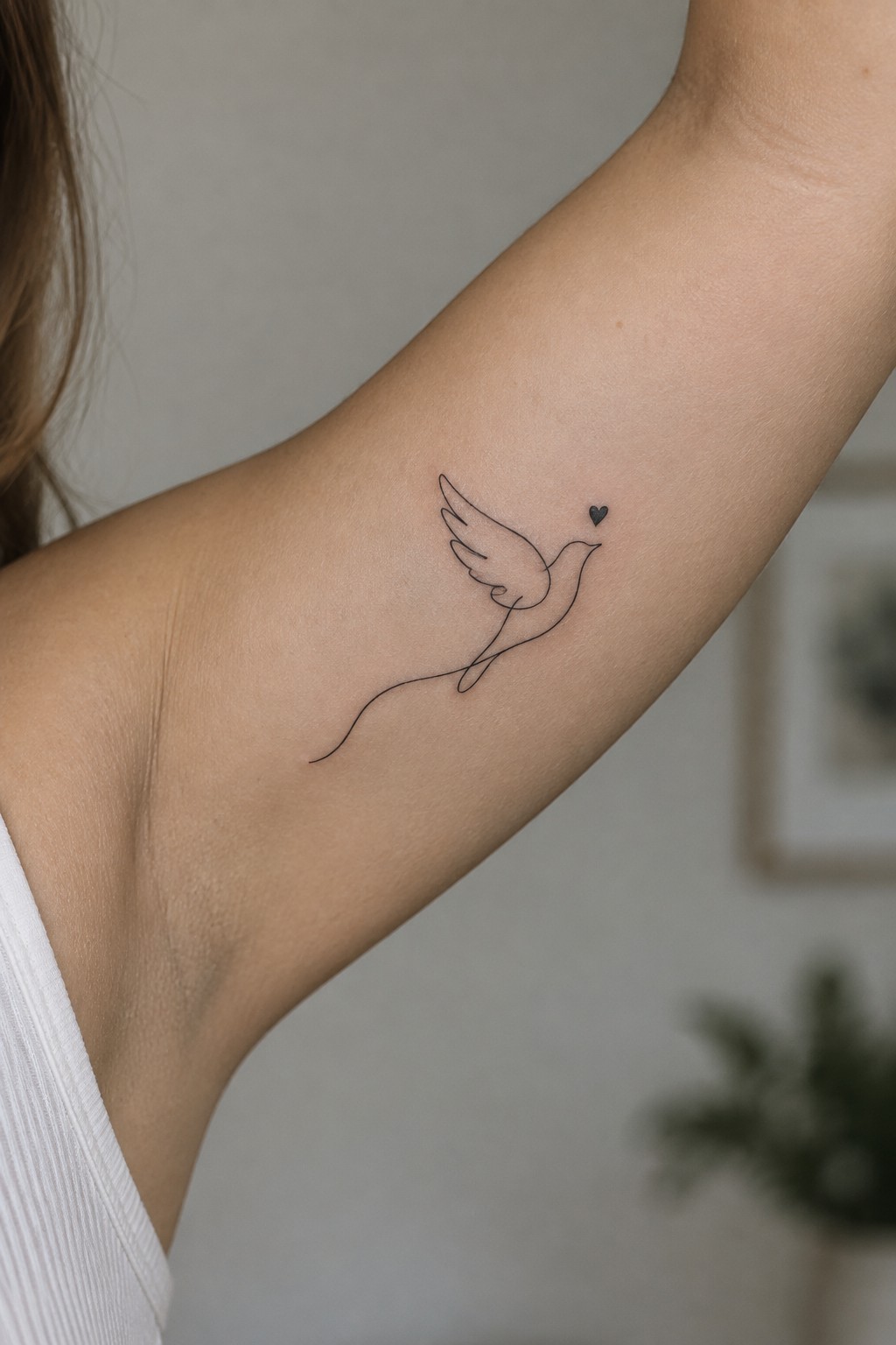 Minimalist line-art dove tattoo with heart on upper arm in white top