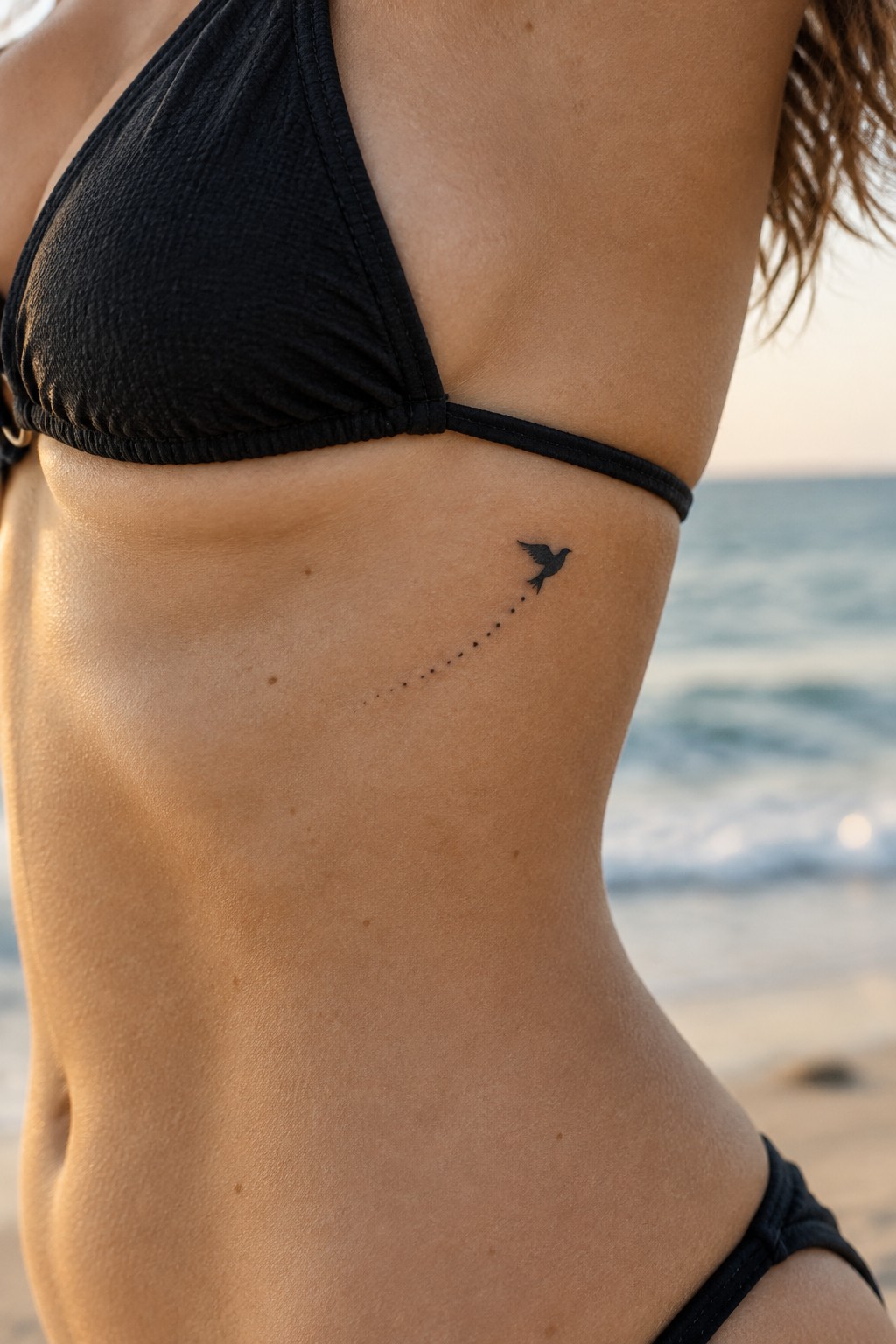 Minimalist black bird silhouette with dotted trail tattoo on the side of the ribcage