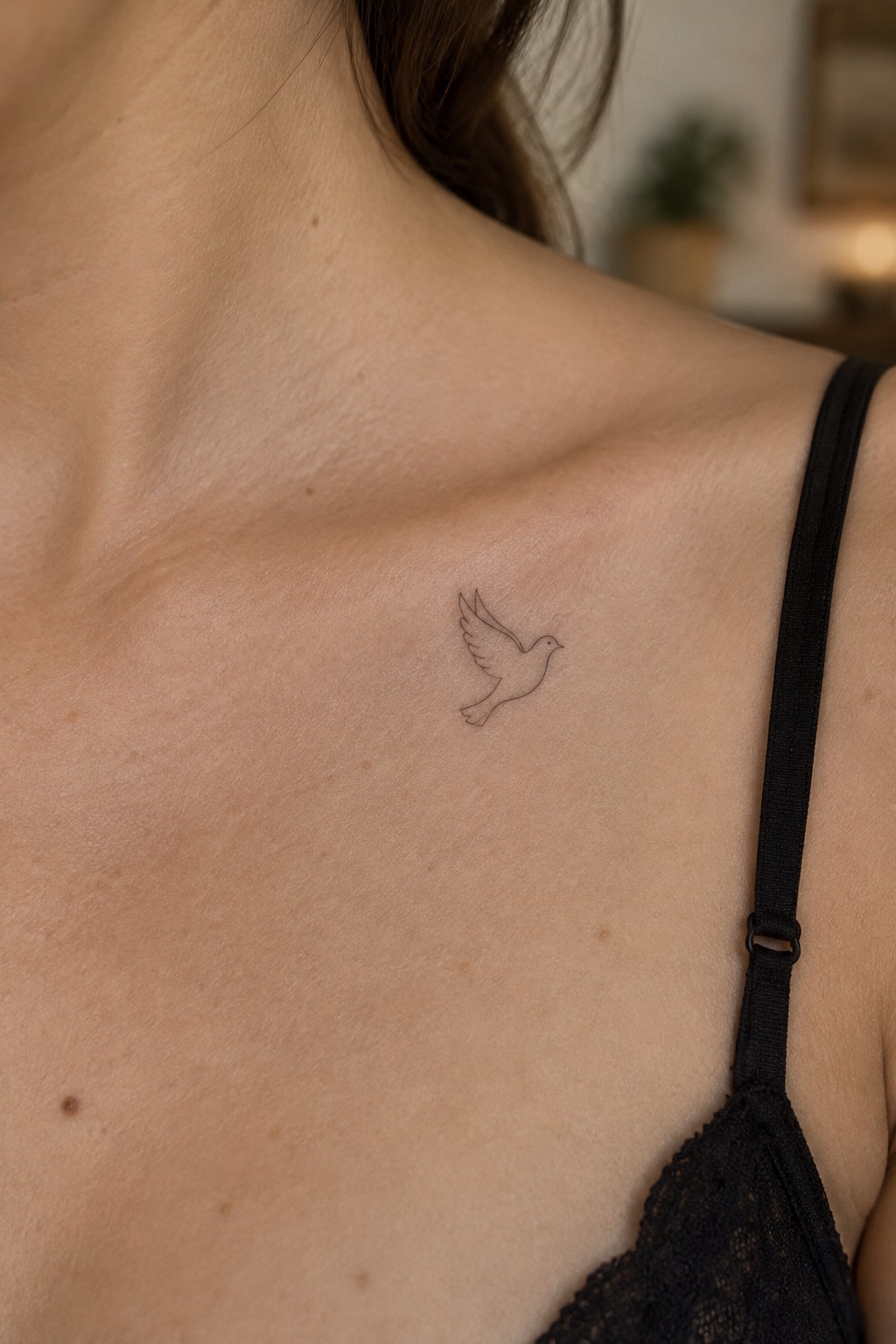 Minimalist line drawing of a flying dove tattoo placed on the upper chest near the collarbone