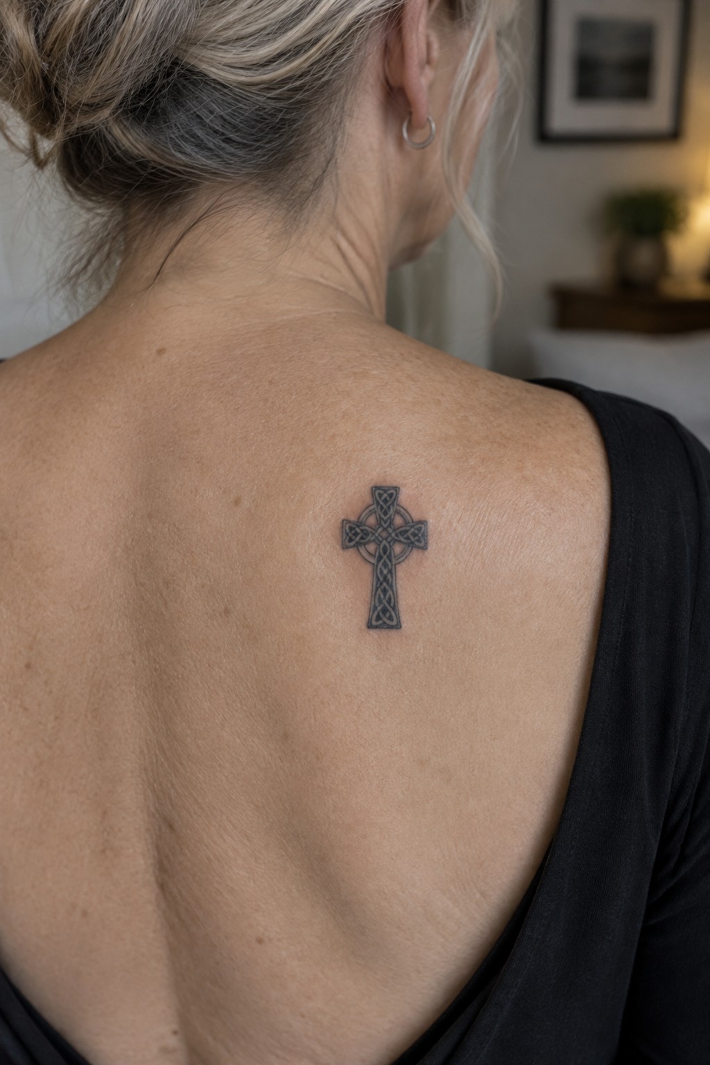 Blonde woman in black top with Celtic cross tattoo on upper back