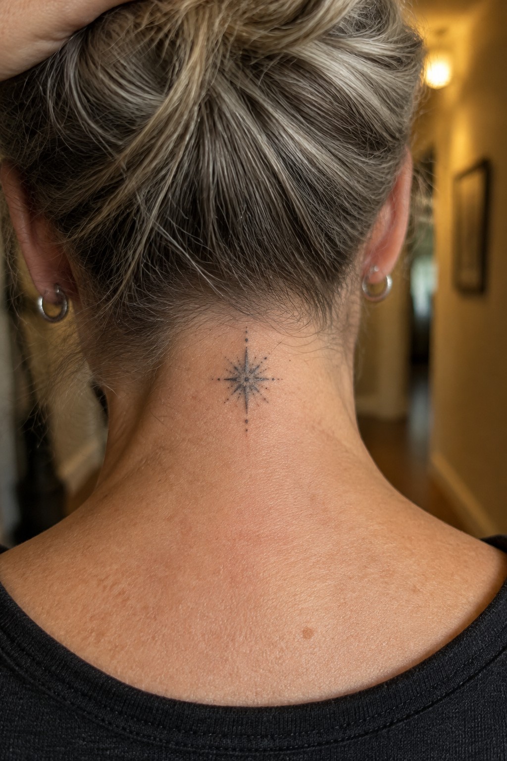Blonde hair in bun with black star tattoo on neck and hoop earrings