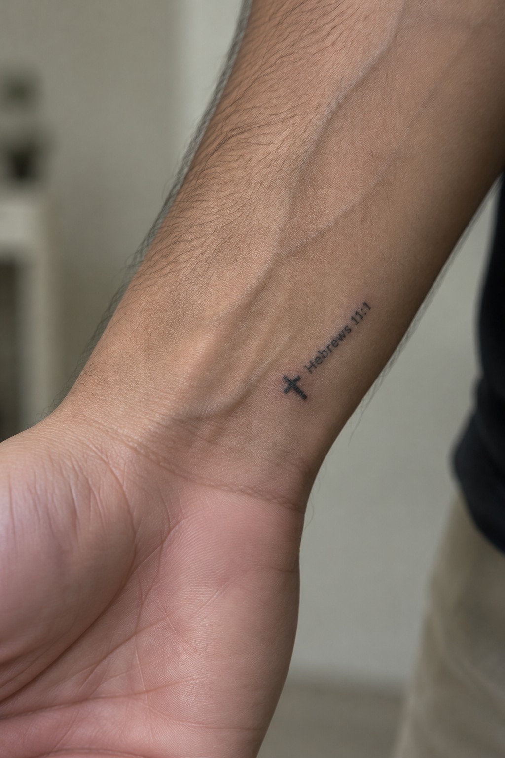 Forearm with small cross tattoo and Hebrews 11:1 text on skin