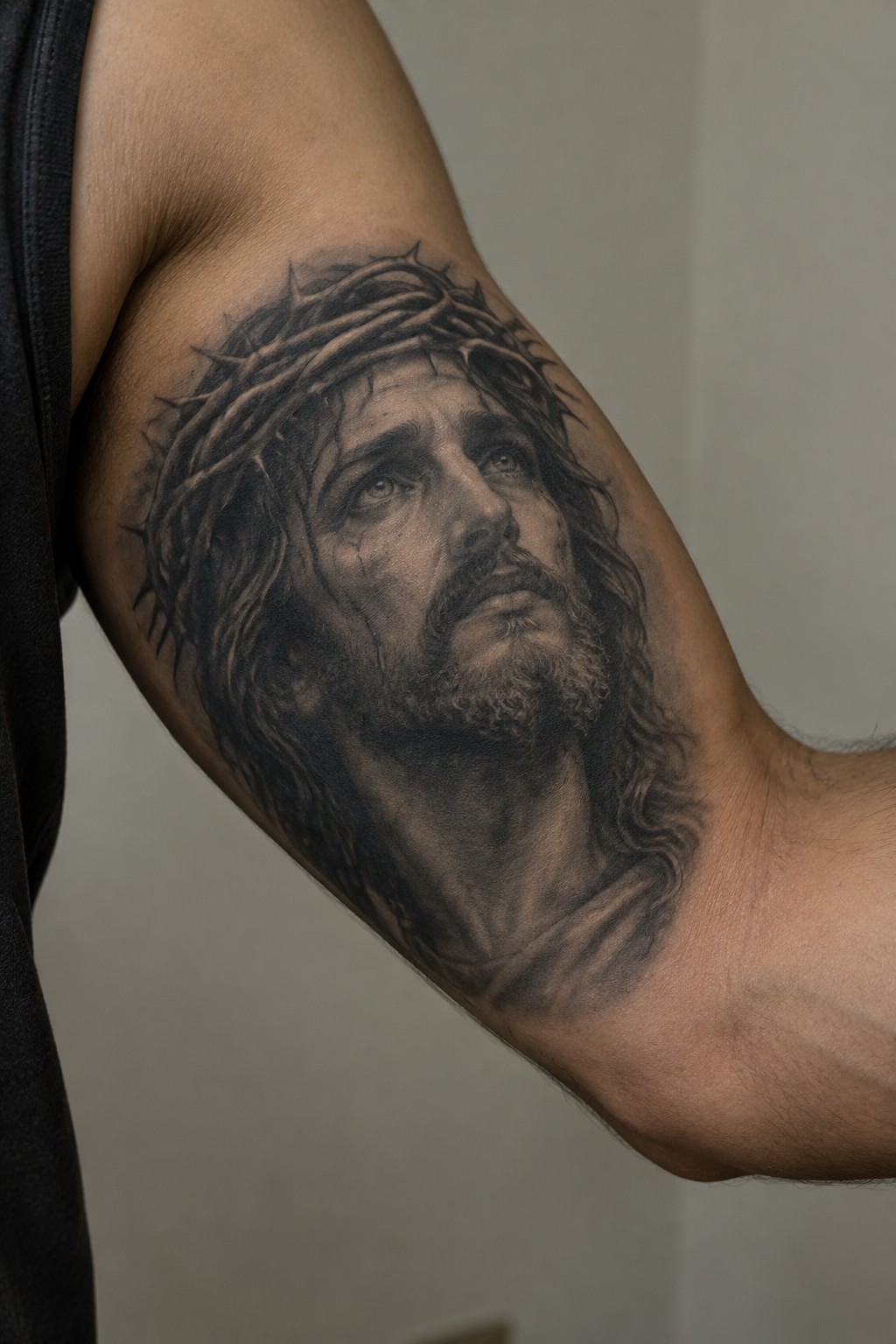 Realistic black and grey Jesus Christ portrait with crown of thorns on the upper arm