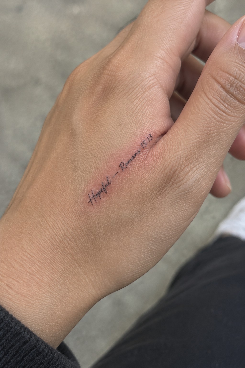 Close-up of a hand with black cursive tattoo
