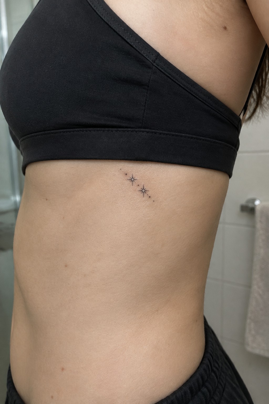 Black sports bra on torso with three small star tattoos on ribs