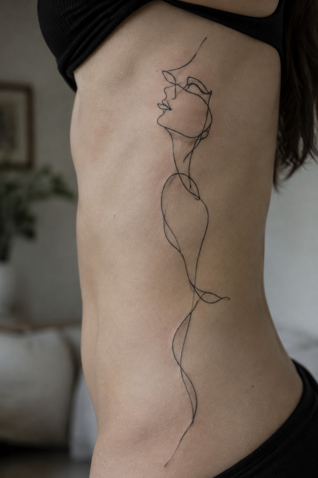 minimalist continuous line tattoo of a woman's profile and abstract body flowing down the side torso