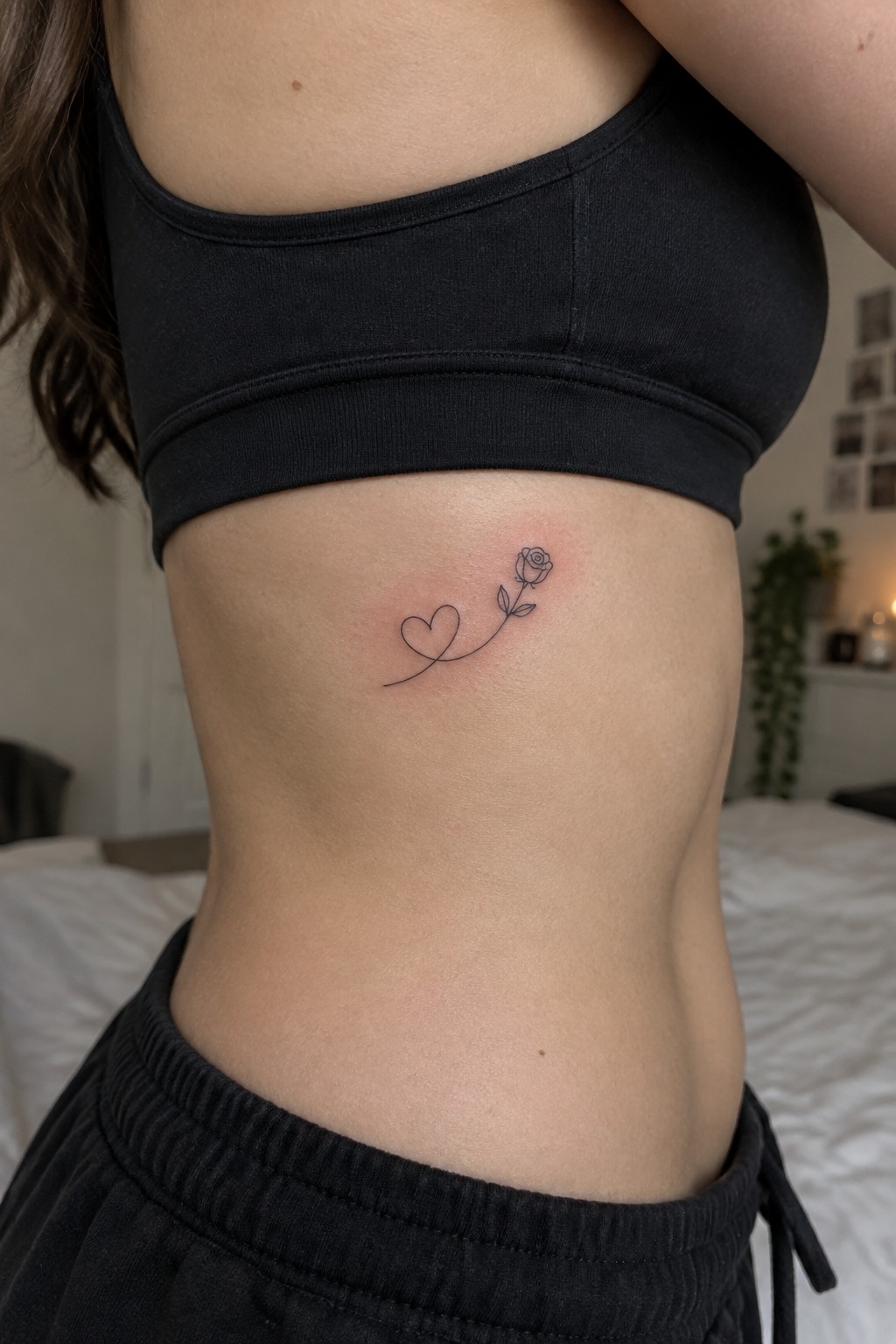 Woman in black crop top with heart-rose line tattoo on ribs