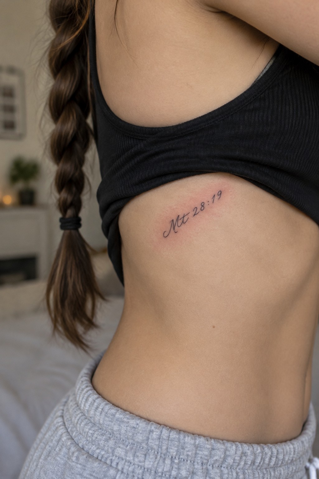 Small cursive tattoo of Mt 28:19 on the side of a torso under the arm