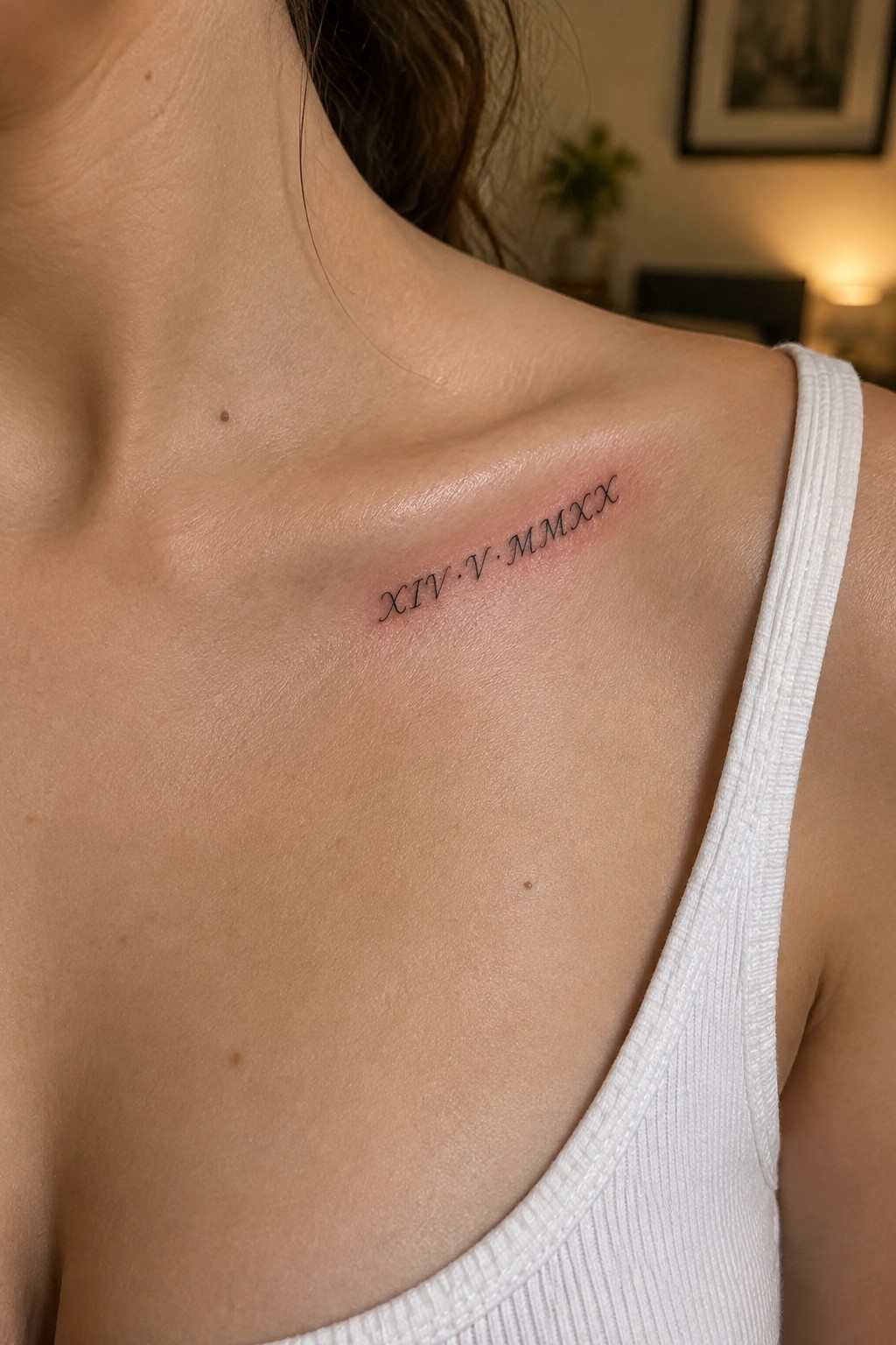 Black Roman numeral tattoo XIV·V·MMXX on shoulder above white tank top strap