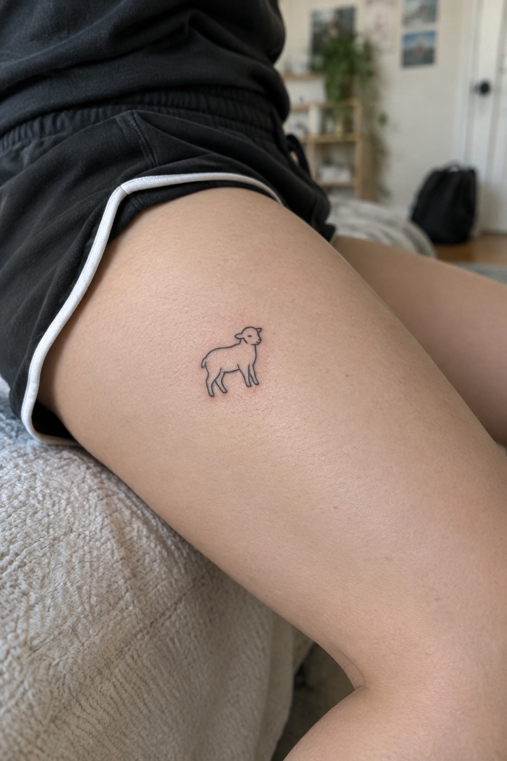 Small line art tattoo of a lamb on the upper thigh