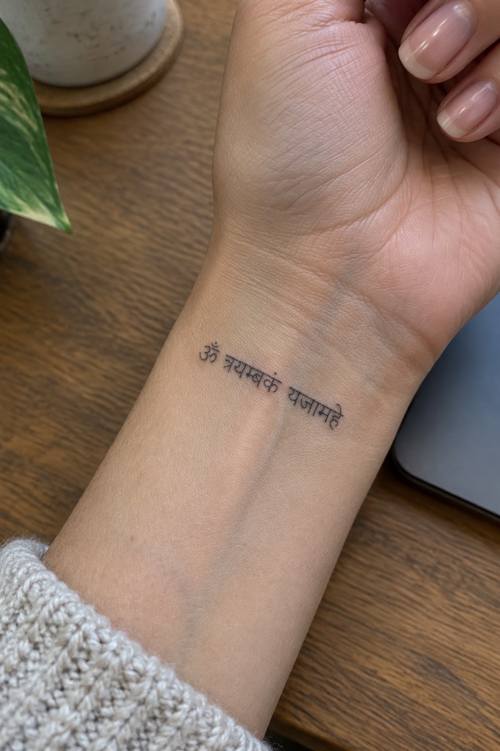 Small black Sanskrit mantra tattoo on the inner wrist.