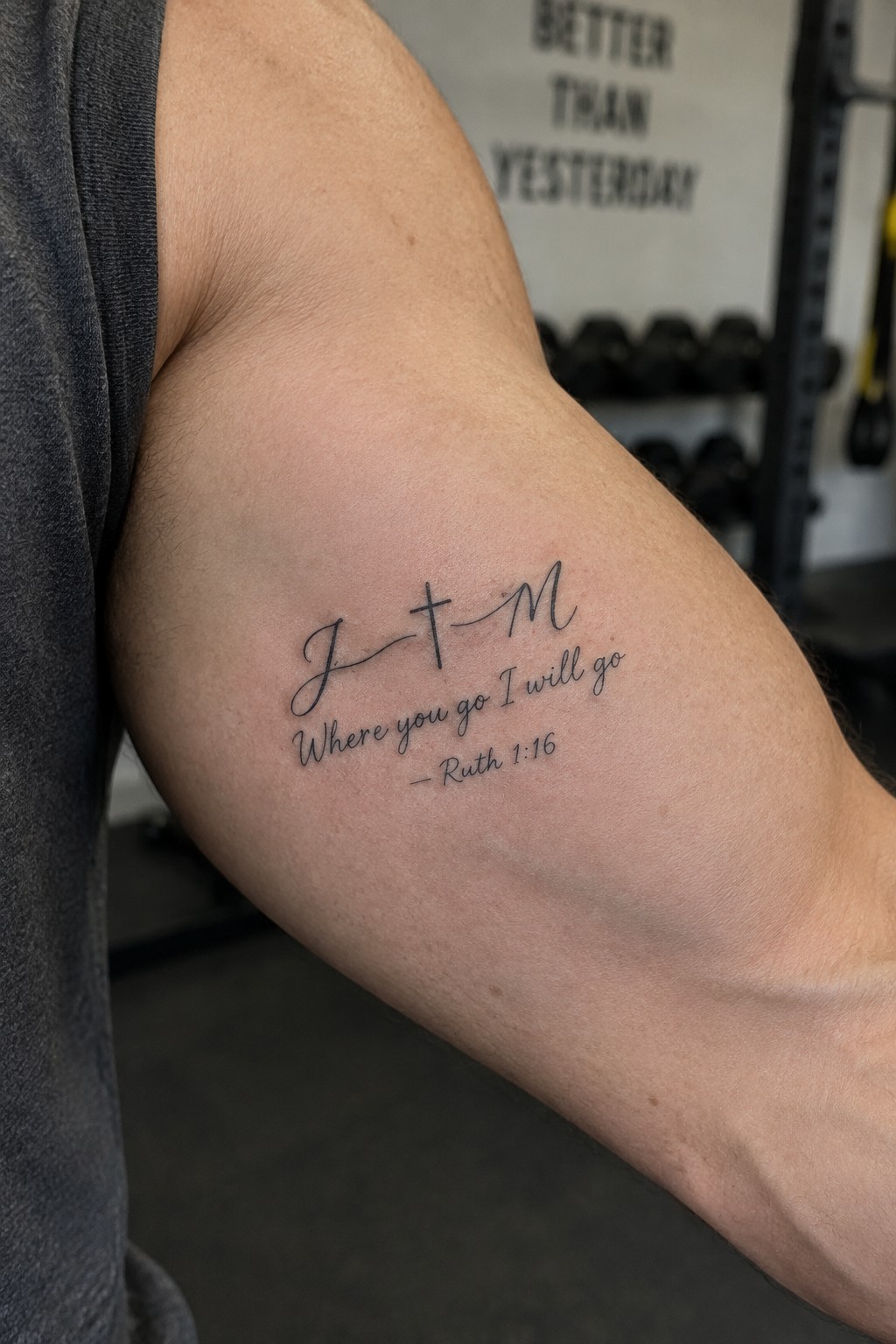 Upper arm tattoo showing cursive initials J and M joined by a cross above the verse Where you go I will go from Ruth 1:16