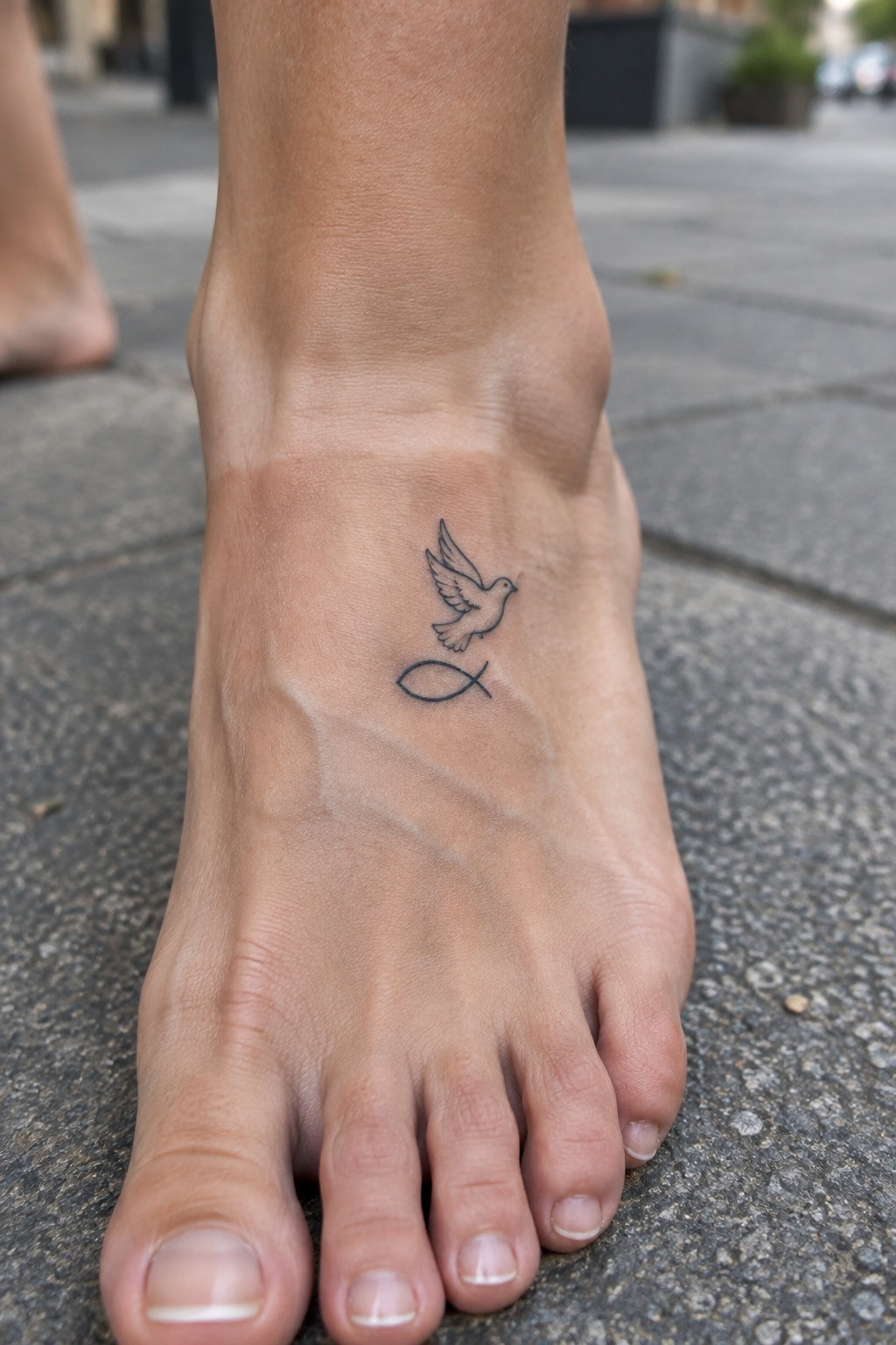 Bare foot with black dove flying above fish symbol tattoo on pavement
