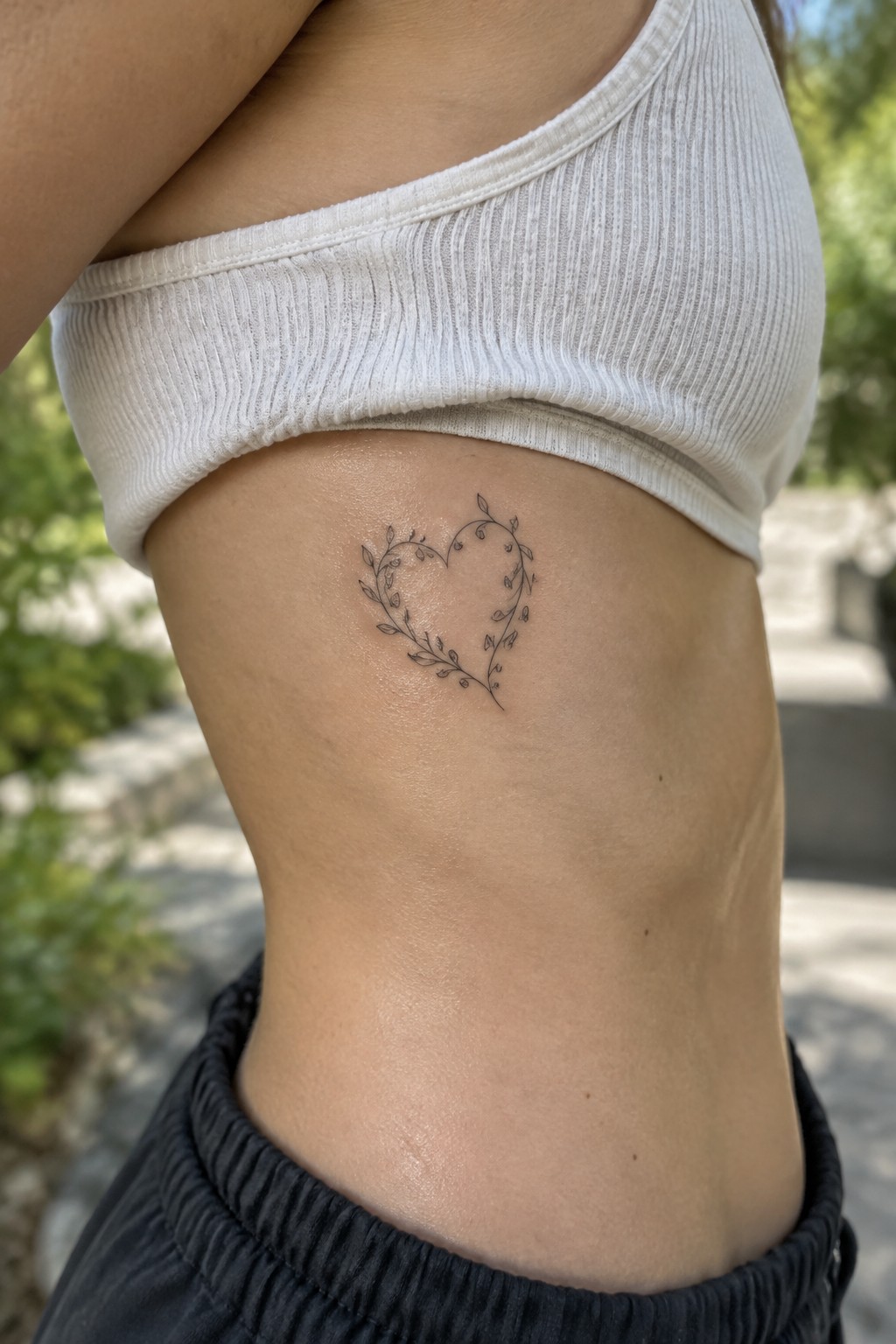 Heart tattoo of leaves and vines below white ribbed crop top