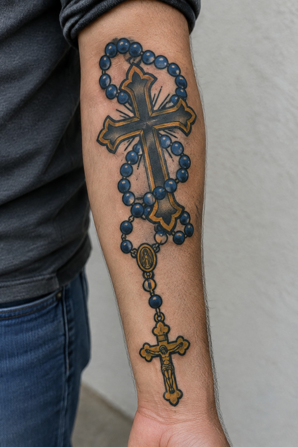Rosary with blue beads and gold cross tattooed on forearm