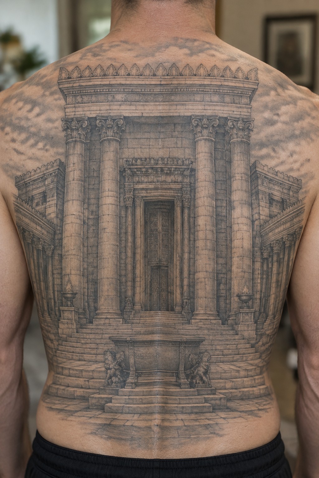 Detailed black-and-gray tattoo of classical temple with columns and cherubs on back