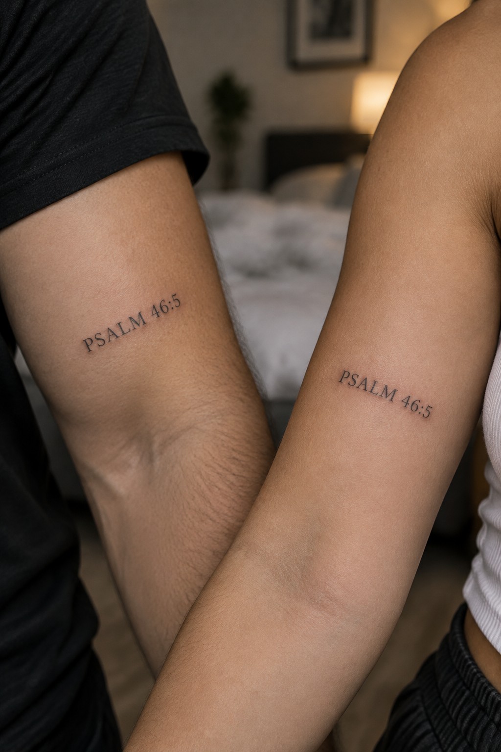 Close up of two inner forearms showing matching Psalm 46:5 tattoos in simple black script, one on a person in a black shirt and one on a person in a white top.
