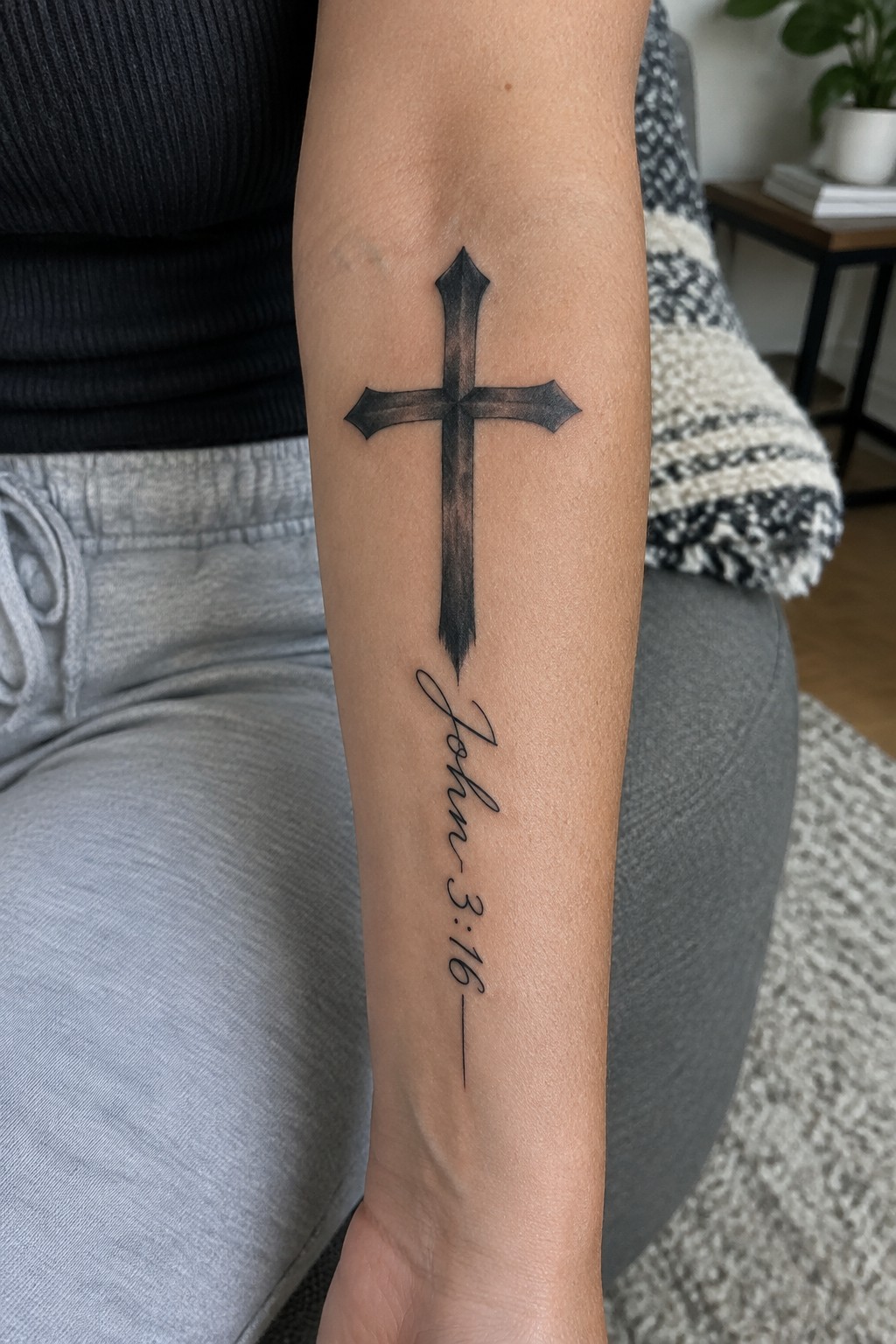Black shaded cross tattoo with “John 3:16” lettering on the inner forearm.
