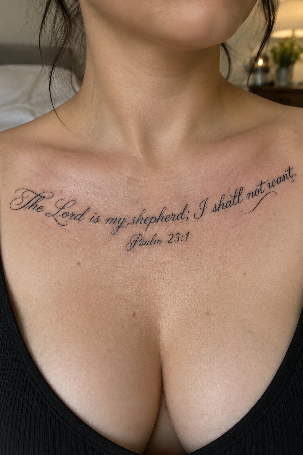 Fine cursive tattoo across the collarbone reading “The Lord is my shepherd; I shall not want,” with “Psalm 23:1” centered below.