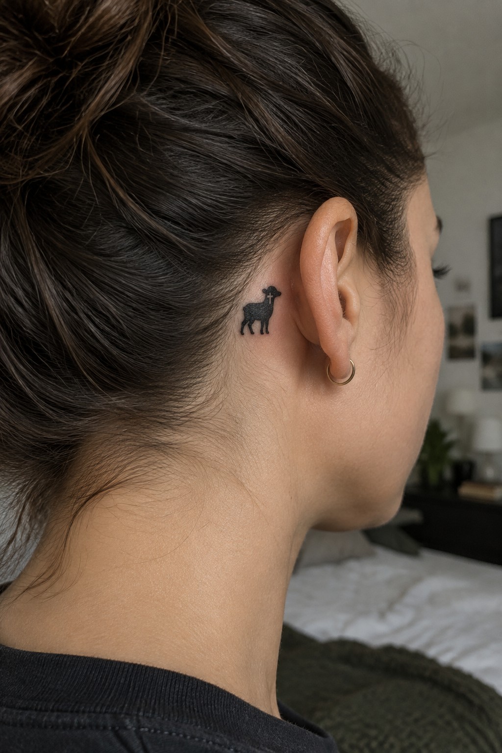 Woman with brown hair in bun and lamb tattoo behind her ear